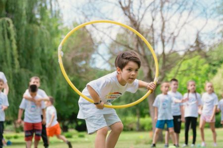 a young boy holding a yellow hula hoop in front of a group of people